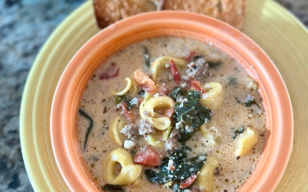 A bowl of tuscan tortellini soup served with crispy cheese bread